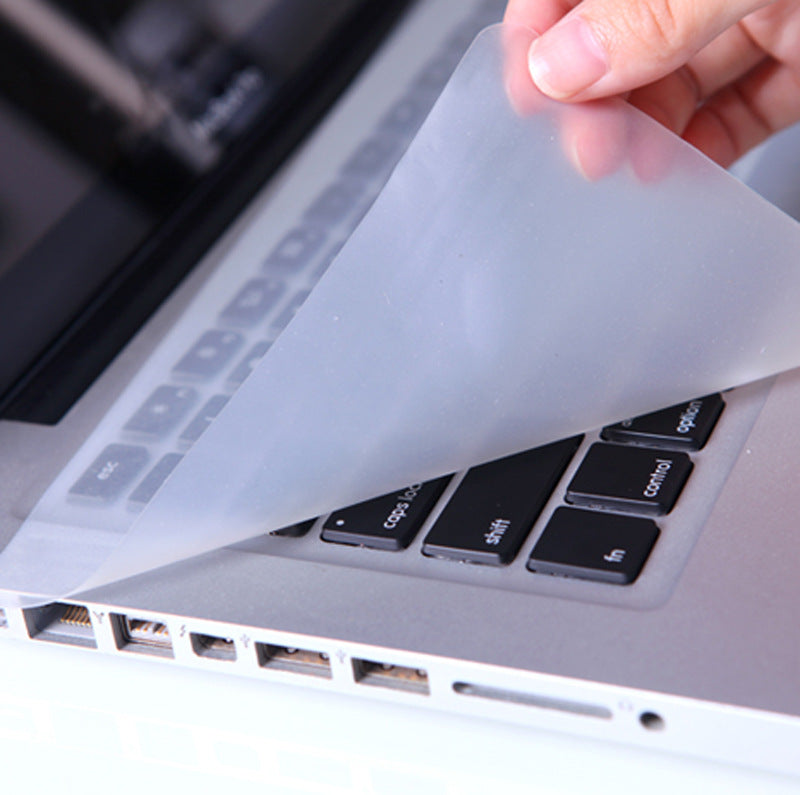 Keyfilm – Hand lifting the clear silicone cover from a silver laptop keyboard, ports visible along the side edge