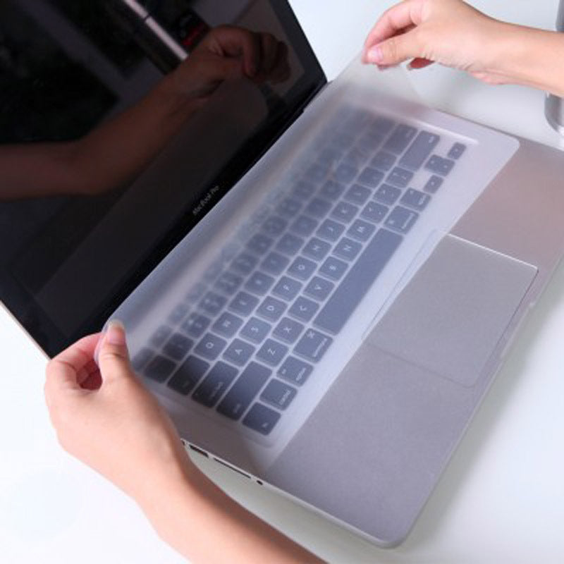 Keyfilm – Two hands placing the frosted keyboard cover over a laptop keyboard and trackpad on a white desk