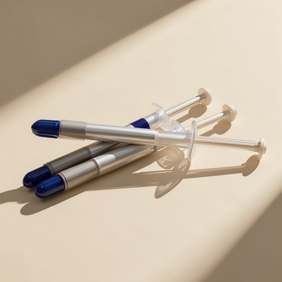 Heatpaste 1G CPU thermal paste: three silicone grease syringes with blue tips resting on a cream surface