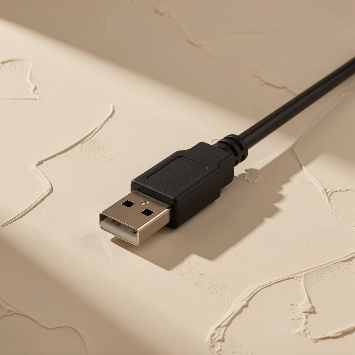 Reachcord Copper USB Extension Cable – close-up of the male USB-A plug and black cable on a textured cream plaster surface