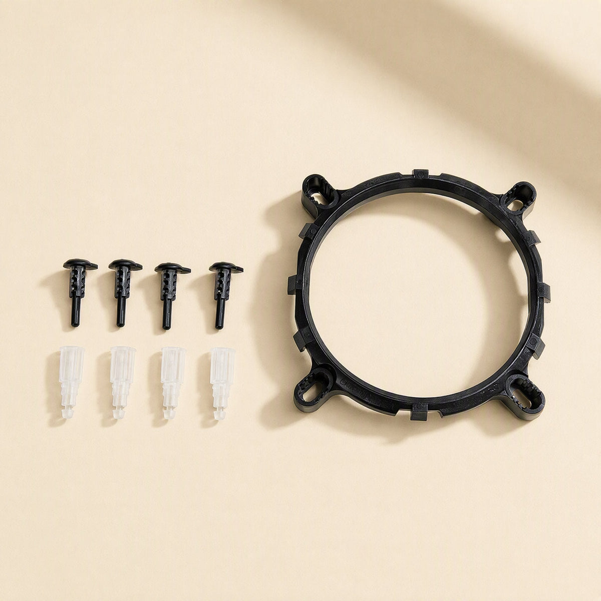 Metalbreeze – Black plastic mounting ring with four black pegs and four clear plastic pins laid out on a beige surface