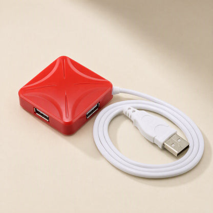Portcluster – Red square hub with X-shaped ridges, two ports showing and a white cable coiled beside a USB plug