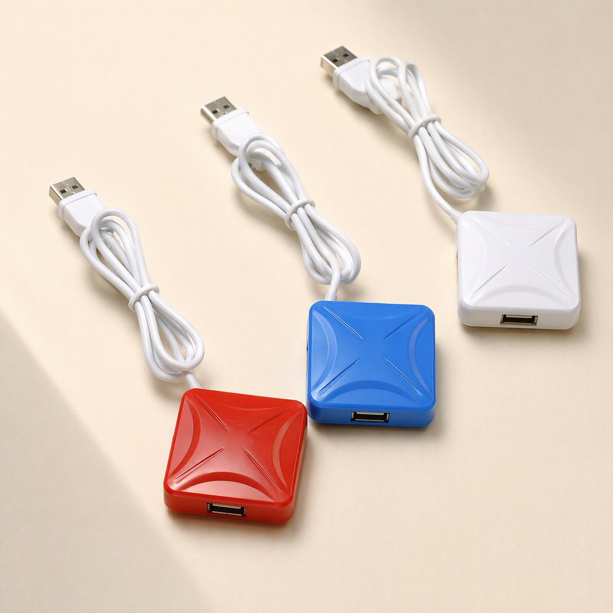 Portcluster – Three square hubs in red, blue and white, each with a looped white cable and USB plug, on a beige surface