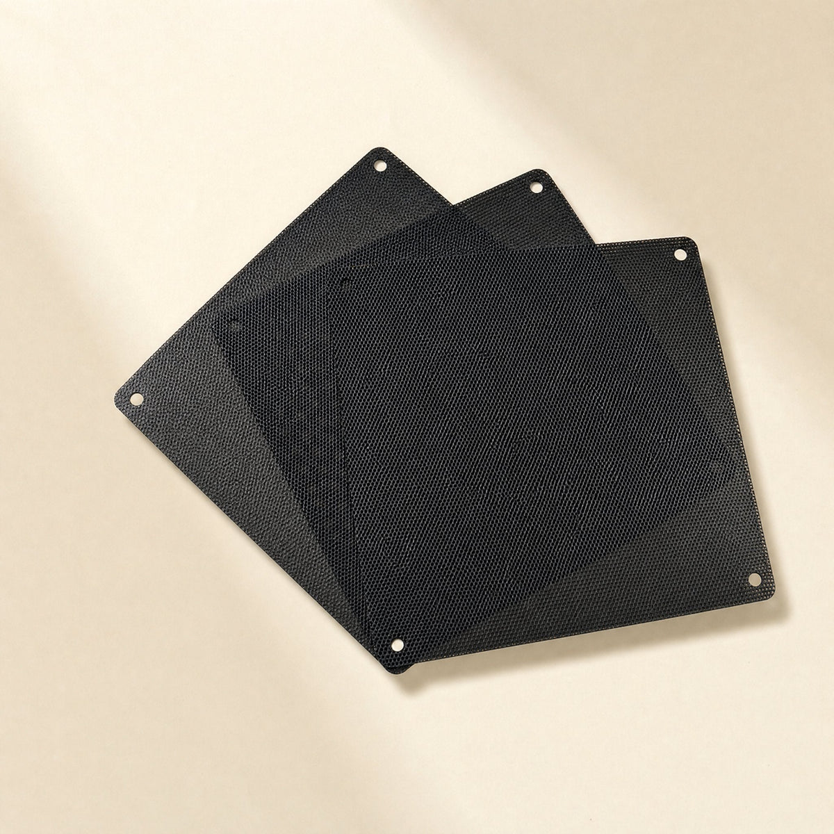 Magmesh – Three black square dust filters with corner screw holes, fanned out on a cream surface