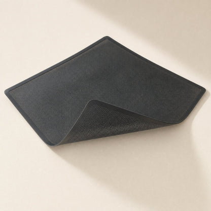 Magmesh – Flexible black filter net lifted at one corner, showing the mesh underside against a beige surface