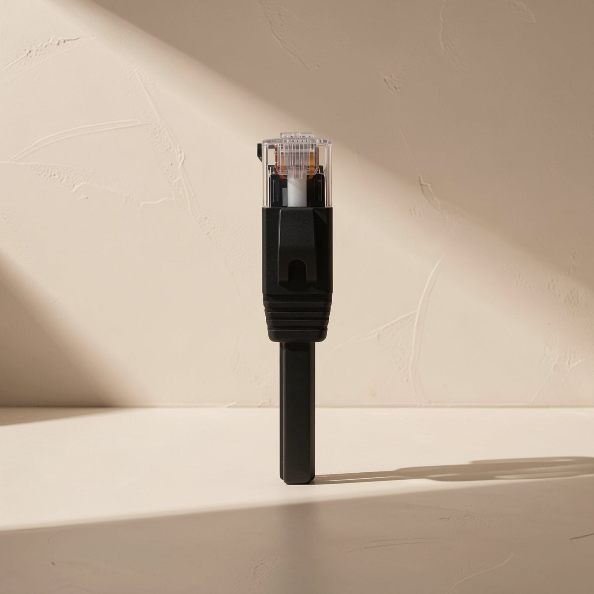 Flatlink – Close-up of a black RJ45 connector with clear plug and strain relief on a flat cable, standing upright