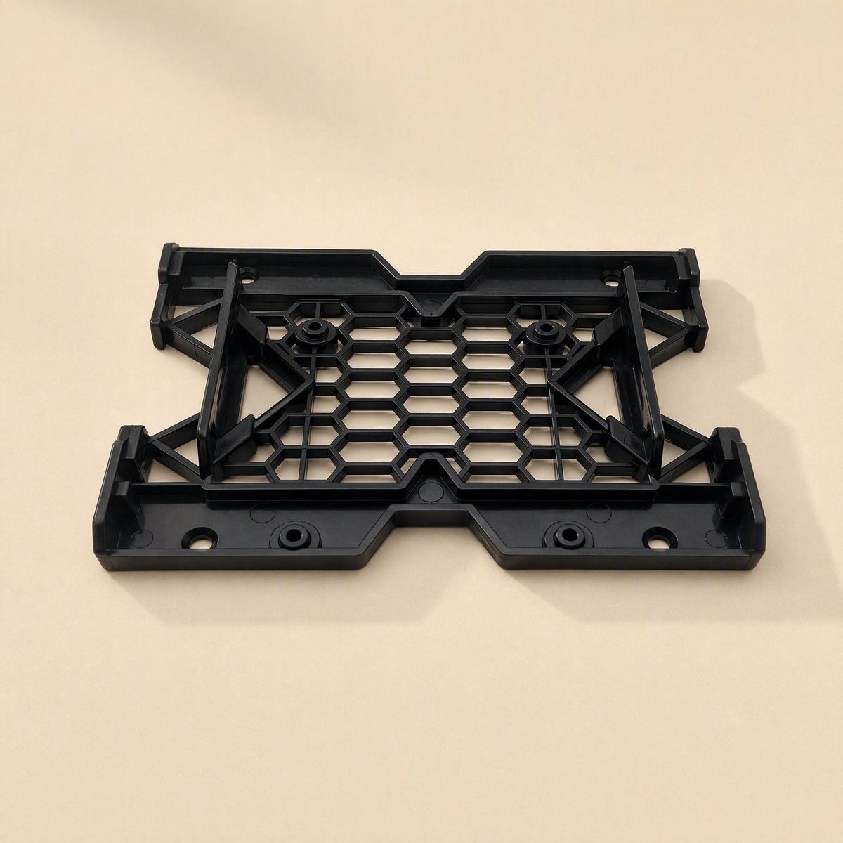 Drivecradle – Black bracket tilted to show its raised side rails and mounting posts on a beige background