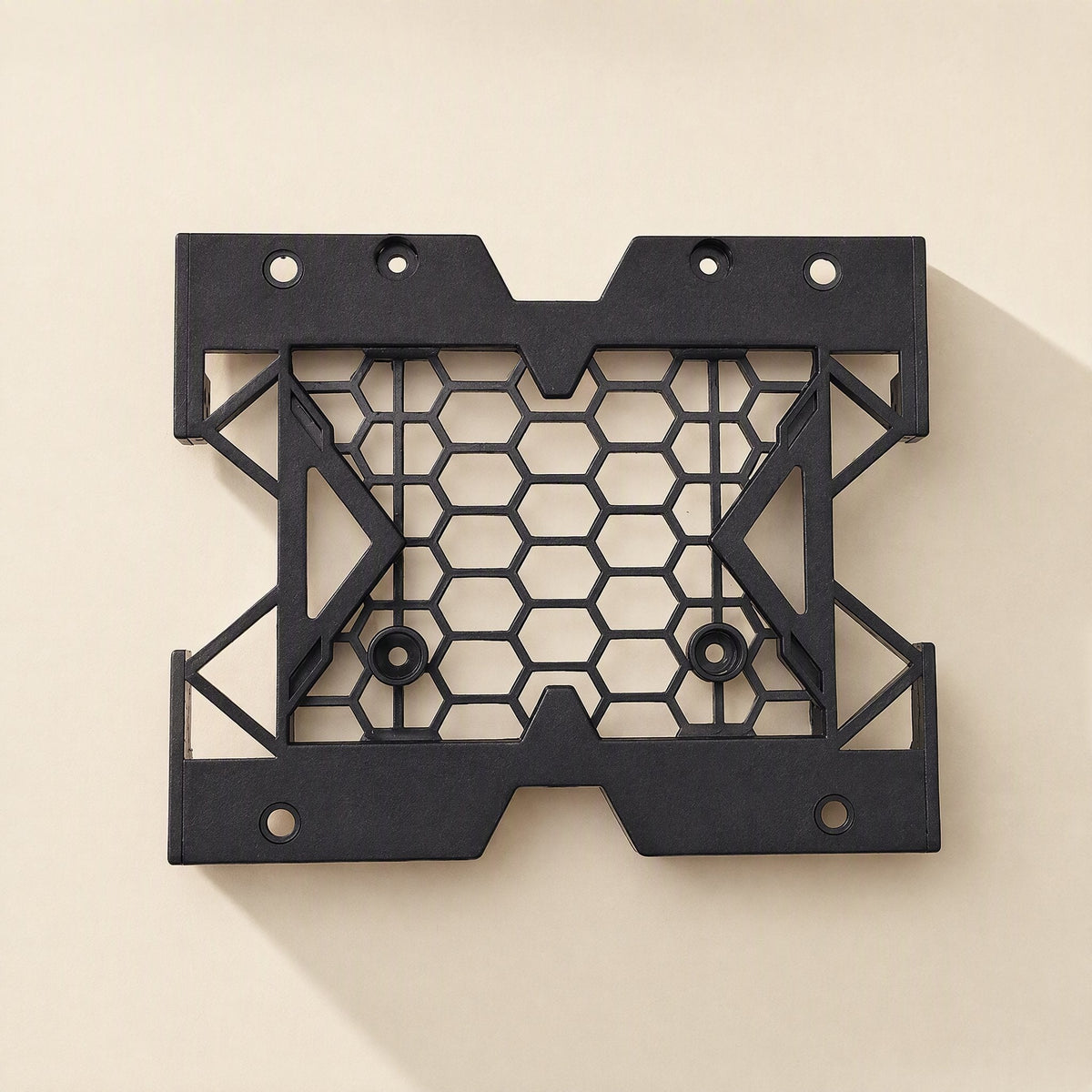 Drivecradle – Black hexagon-mesh bracket viewed flat from above, empty, with four screw holes along the edges
