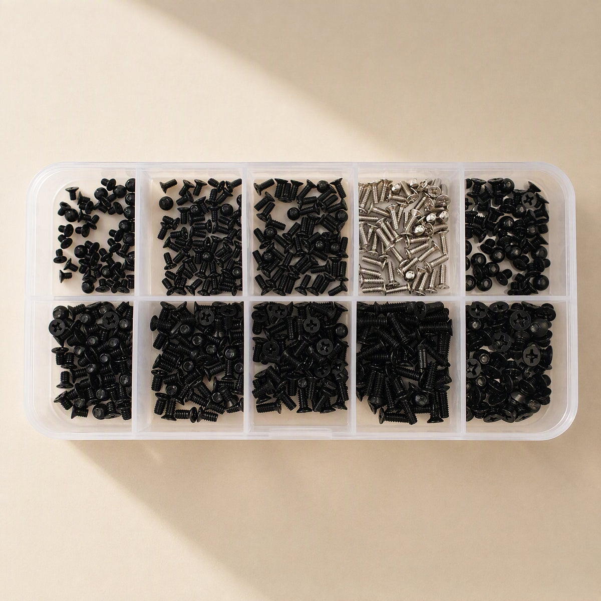 Microfast Blackened Countersunk Laptop Screws in a ten-compartment clear case, top view with soft shadow