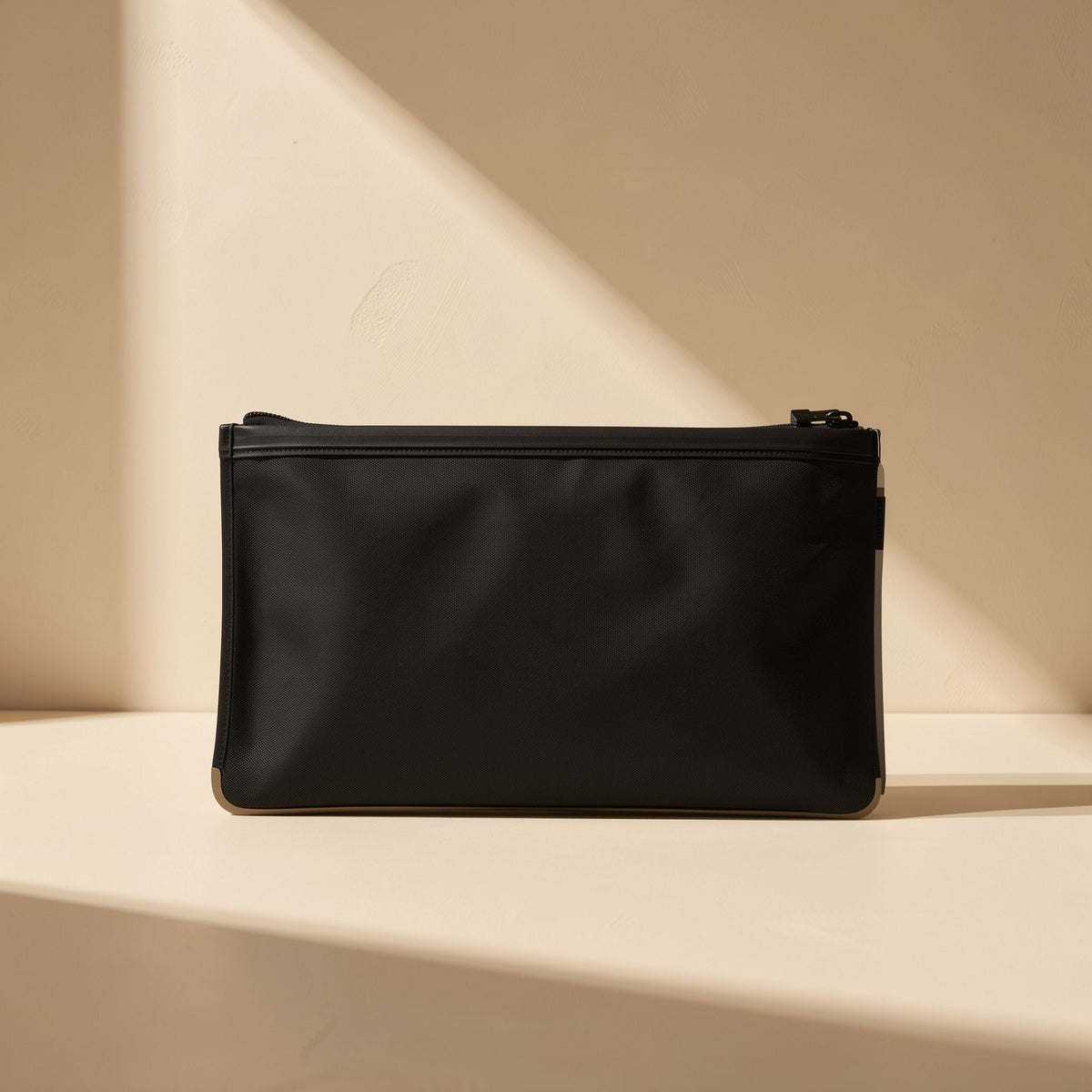 Dustmesh – Black zippered pouch with a matte finish standing on a cream surface in angled light