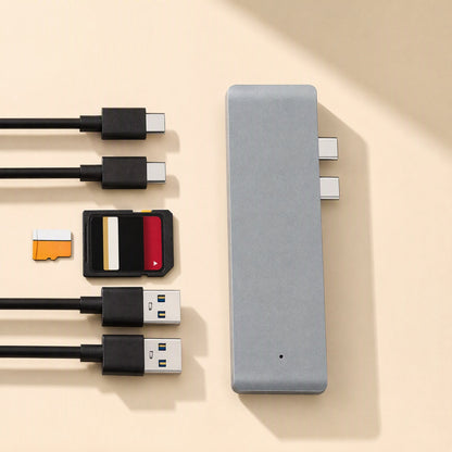 Linkdock – Grey dock shown from above with two USB-C plugs, SD and microSD cards, and two USB-A cables beside it