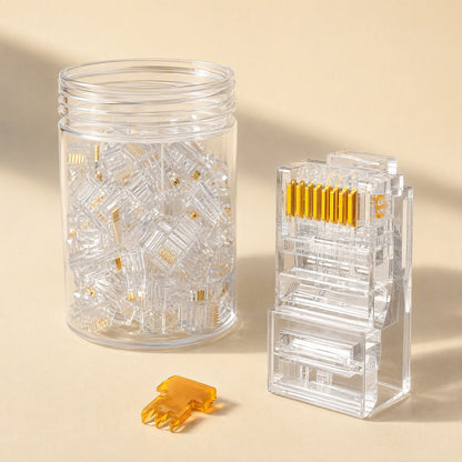 Netclick – Clear RJ45 connector with gold pins standing upright next to a jar of loose connectors and an orange part