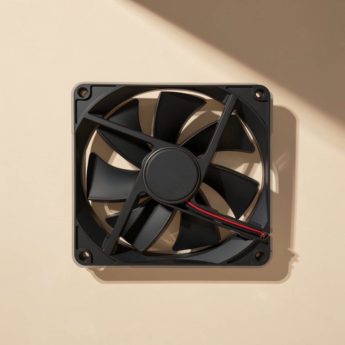 Bladechill – Square black fan mounted flat against a beige wall, angled view showing corner screw holes and shadow