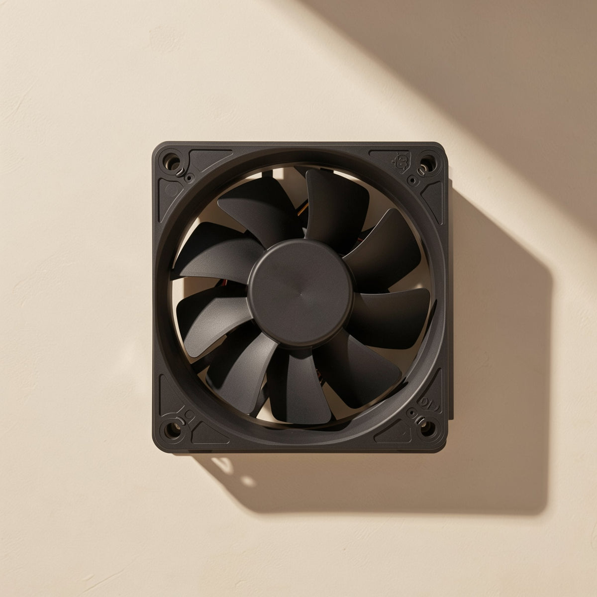 Chillspin – Top-down view of the black fan's front face with seven blades and corner mounting holes on a cream surface