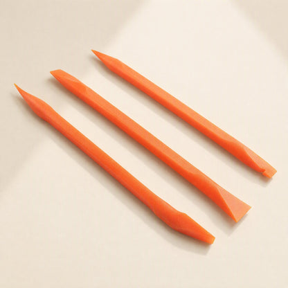 Prywise – Three orange pry tools with pointed and chisel tips arranged side by side on a soft beige backdrop