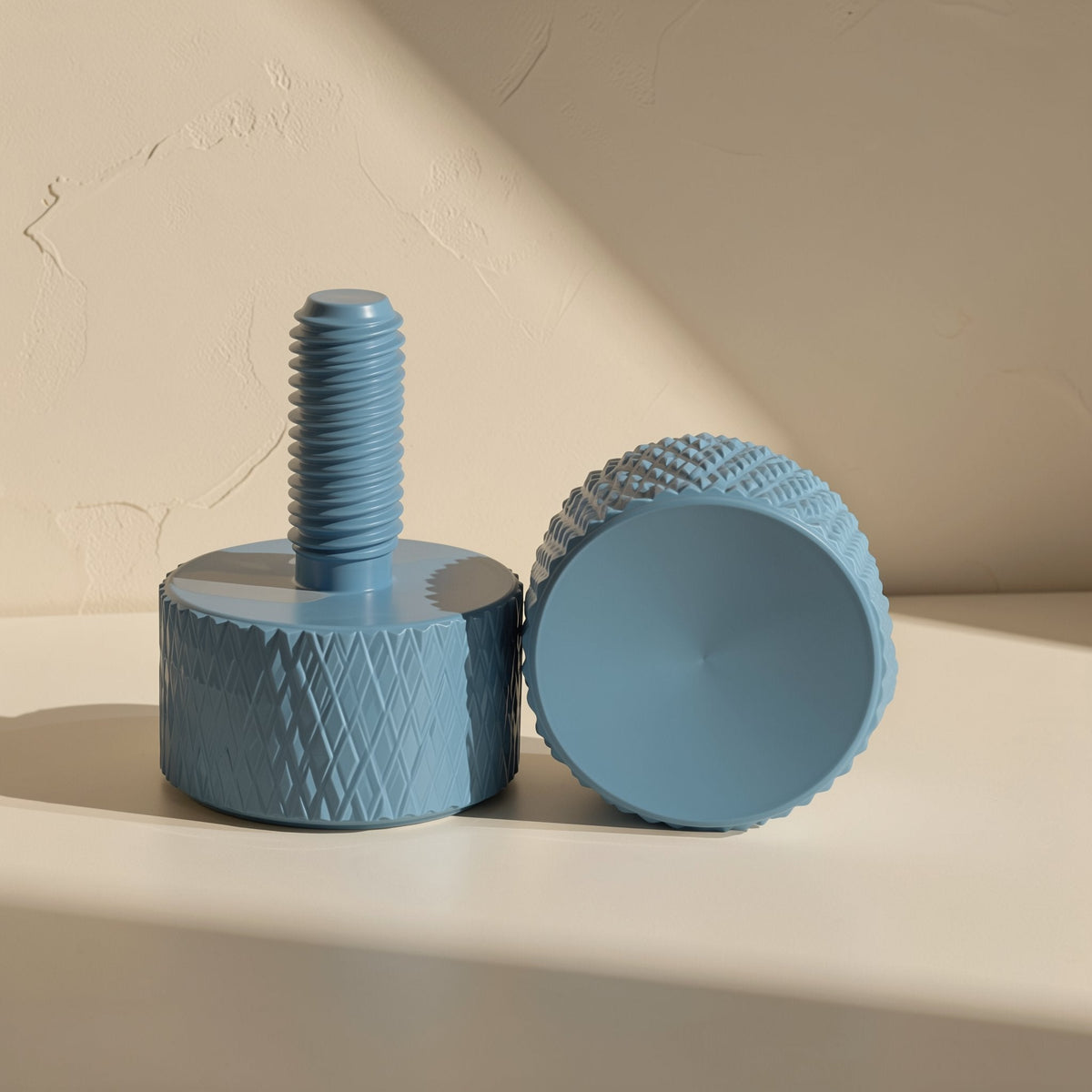 Gripturn – Blue knurled thumb screw standing upright beside another resting on its side, showing diamond grip pattern