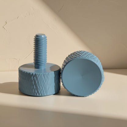 Gripturn – Blue knurled thumb screw standing upright beside another resting on its side, showing diamond grip pattern