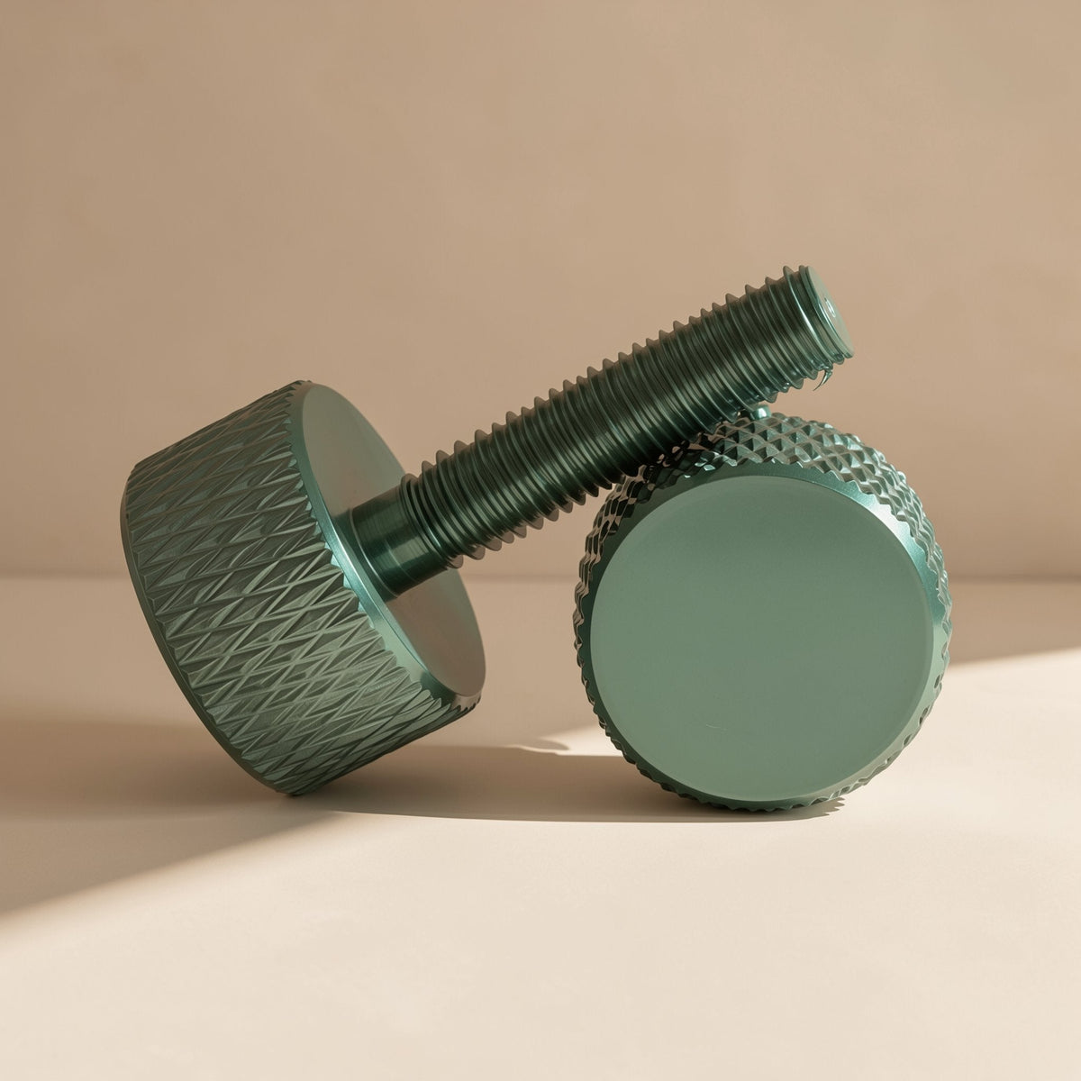 Gripturn – Green knurled thumb screw leaning on a second one, showing threaded shaft and flat top