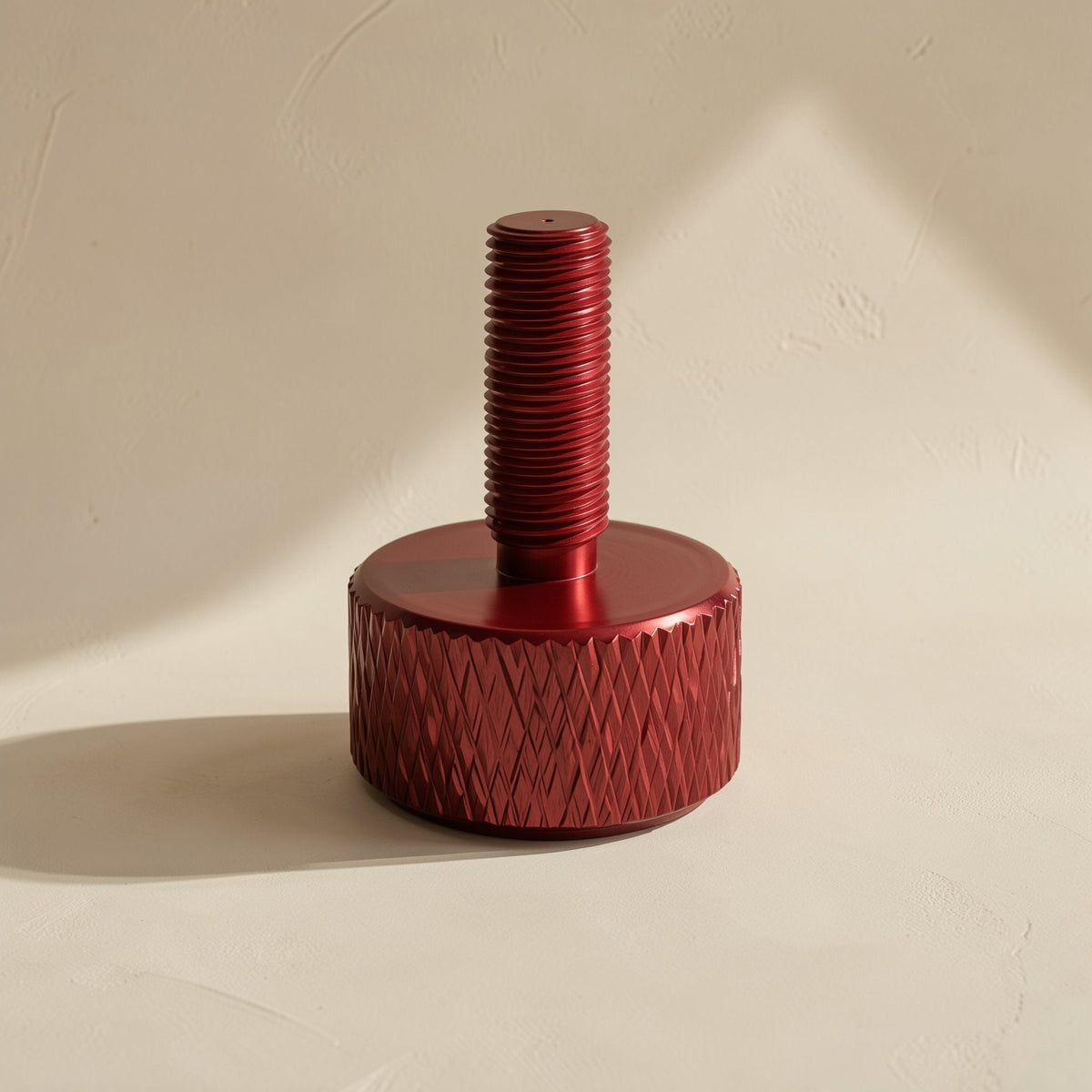 Gripturn – Red knurled thumb screw standing upright, showing diamond-patterned head and threaded shaft