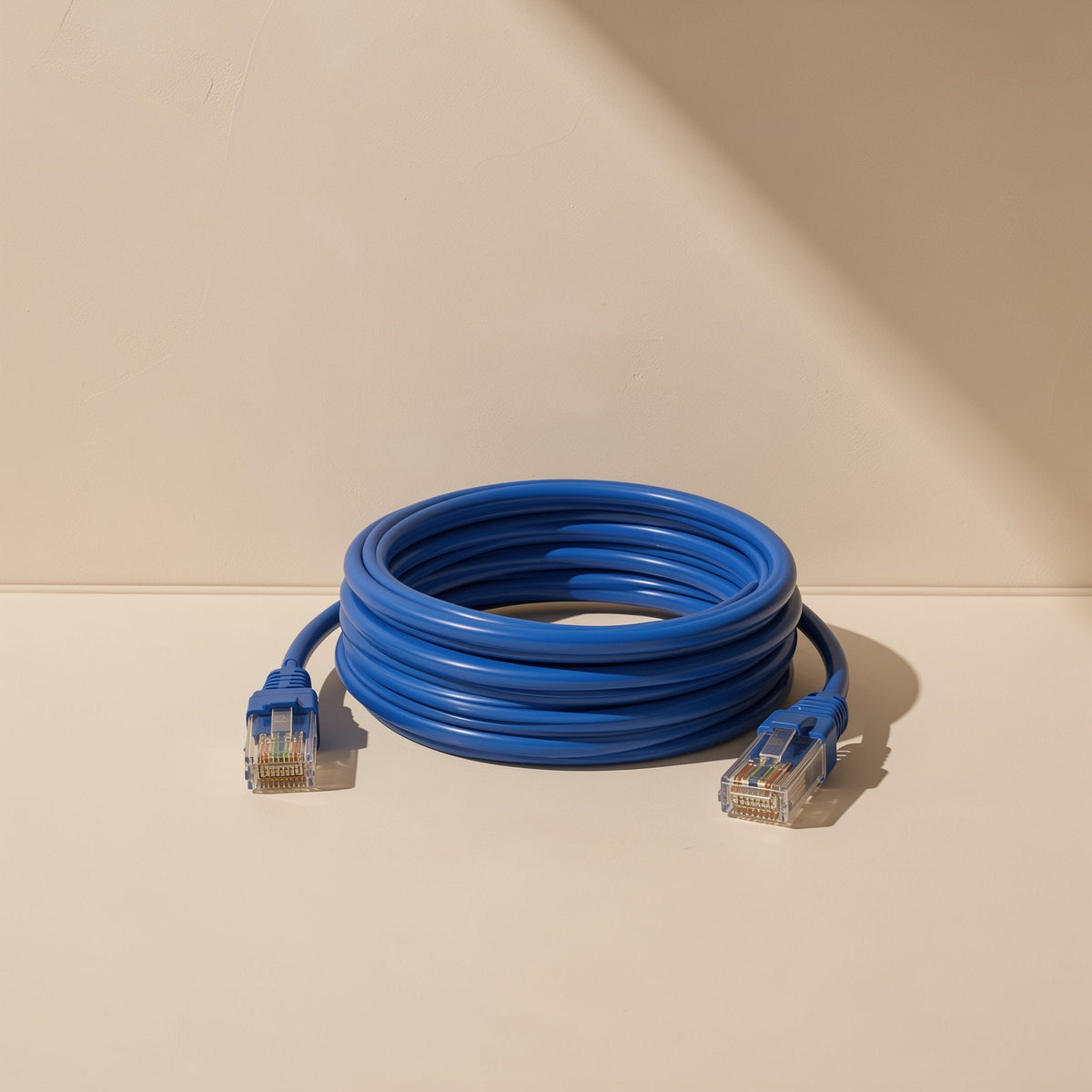 Gigabraid Cat6 Gigabit Ethernet cable, blue, coiled in a loop with RJ-45 connectors on a beige backdrop