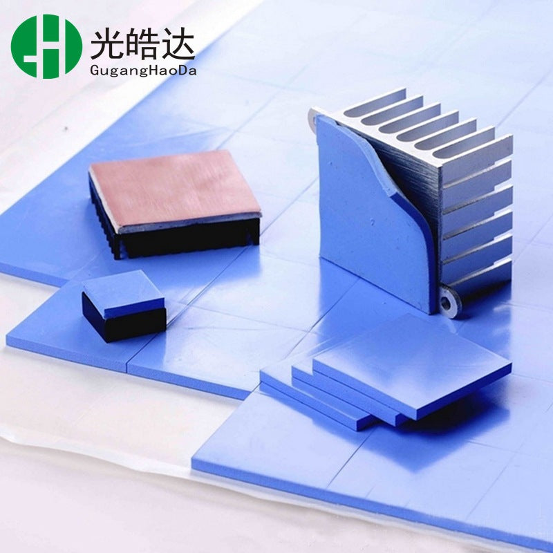 Gapflow – Blue thermal pads cut to different sizes beside a finned aluminum heatsink and copper-topped components