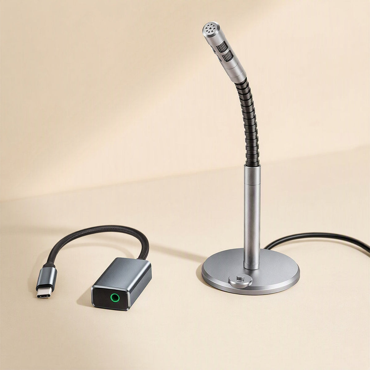 Twintone USB Sound Card – gray USB-C audio adapter with green jack beside a gooseneck desktop microphone on a round stand