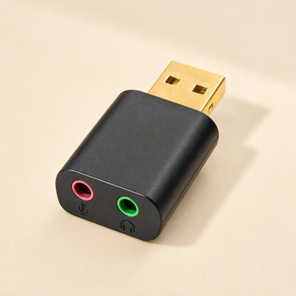 Twintone – Compact black USB audio dongle with gold connector and red and green headphone and mic ports, front view