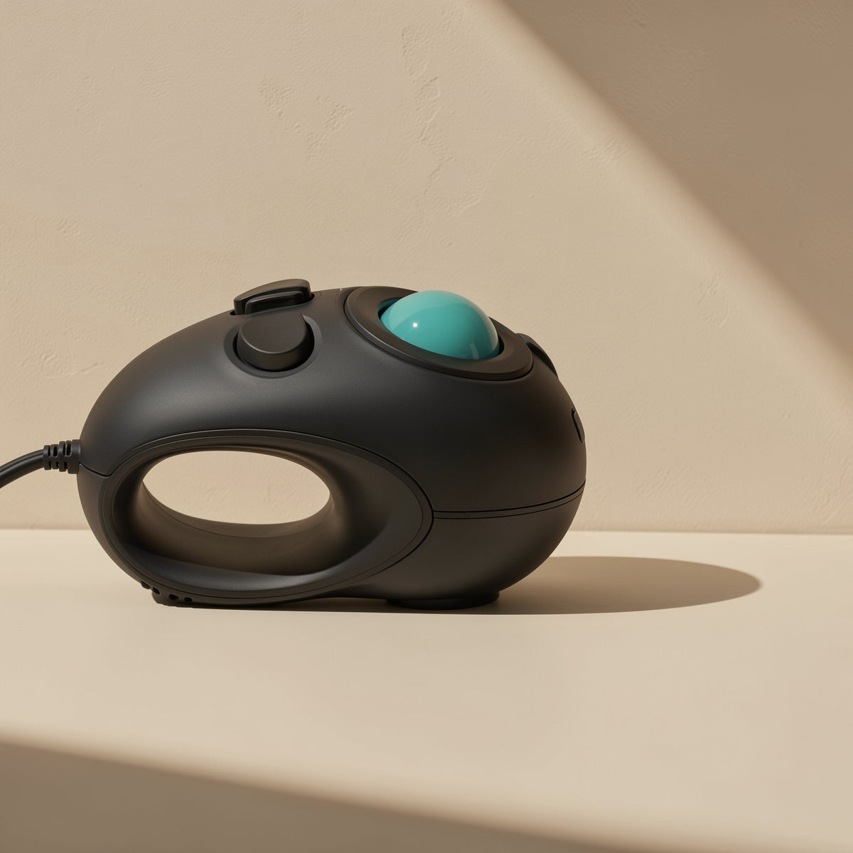 Optiroll Wired Optical Trackball Mouse in black with teal ball, side view showing finger loop on a beige surface