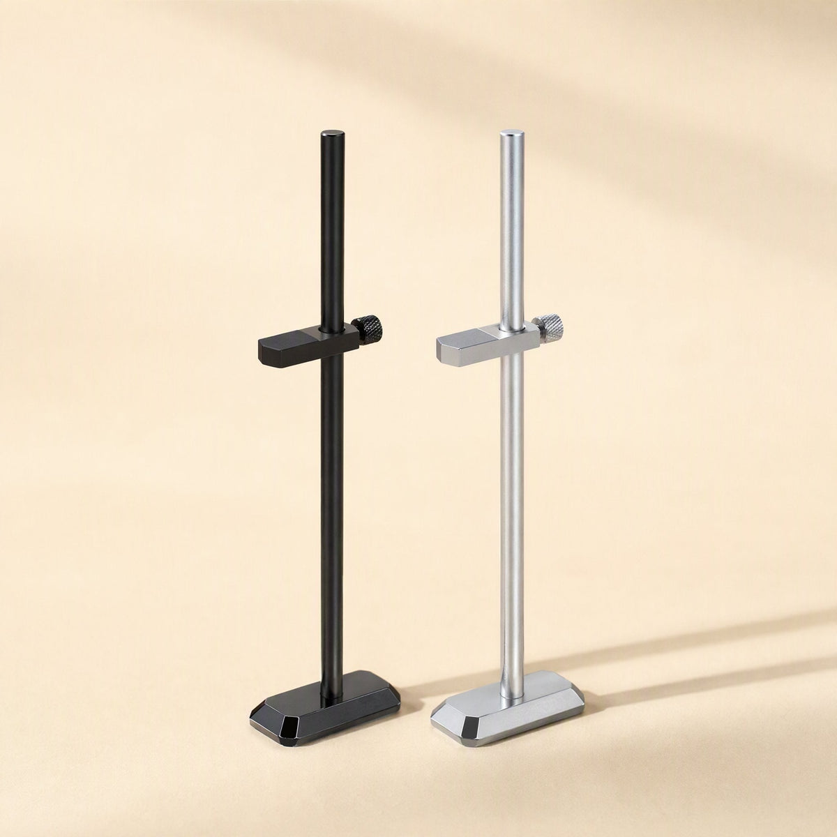 Chipbrace – Black and silver graphics card brackets with angled bases, one clamp arm each, on a warm beige surface