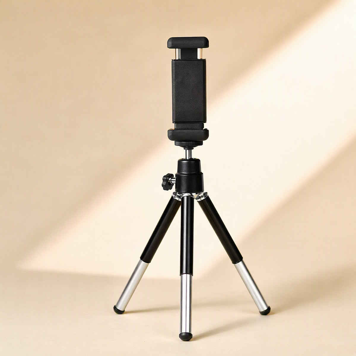 Phoneprop – Tripod stand with black phone clamp attached, extended silver leg sections, on a warm beige background