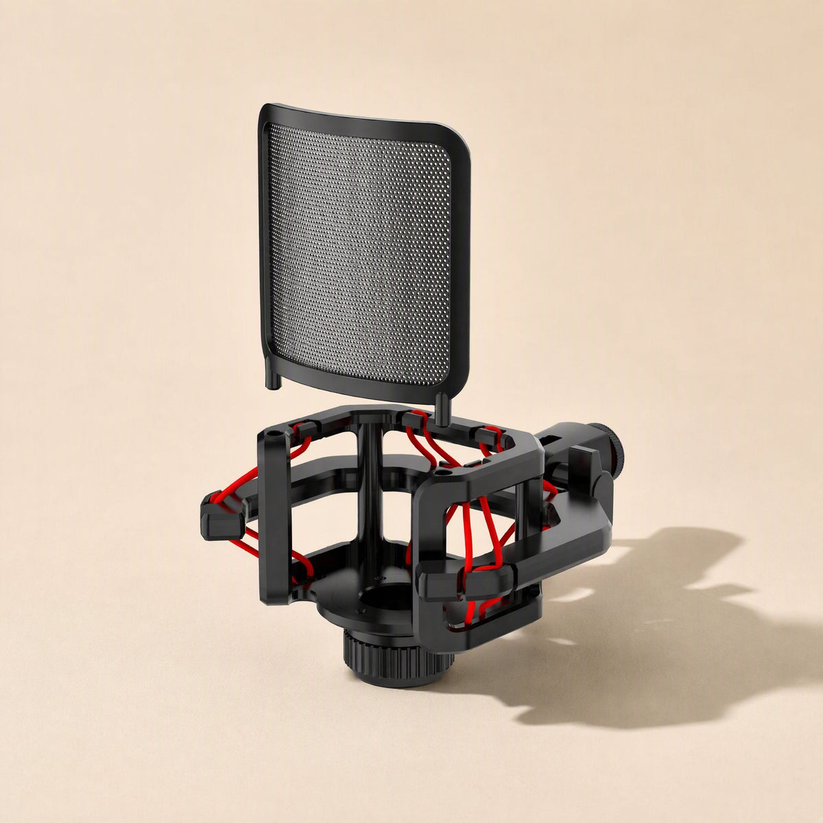 Joltbrace – Black shock mount with red suspension cords and mesh pop filter on a beige background, seen from a slight angle