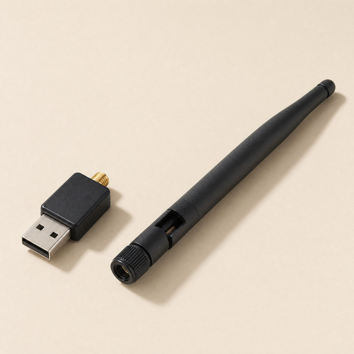 Netplug – Detached black antenna beside the USB adapter body with gold connector, on a beige background