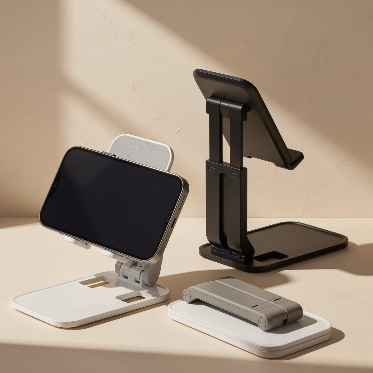 Deskease Alloy Desktop Phone Holder in white and black, one with a phone, one open empty, one folded flat