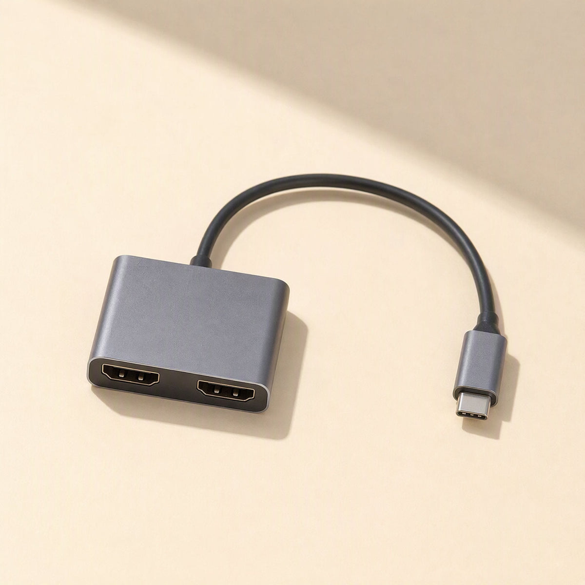 Twinview – Top-down view of gray dual HDMI hub with two HDMI ports and attached USB-C cable on a beige surface