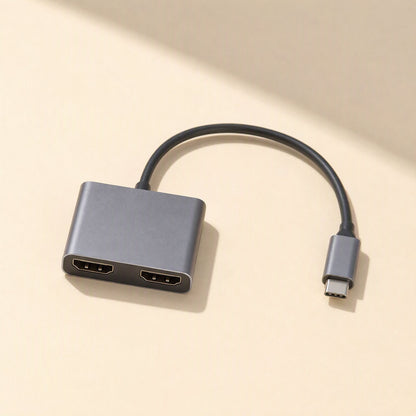 Twinview – Top-down view of gray dual HDMI hub with two HDMI ports and attached USB-C cable on a beige surface