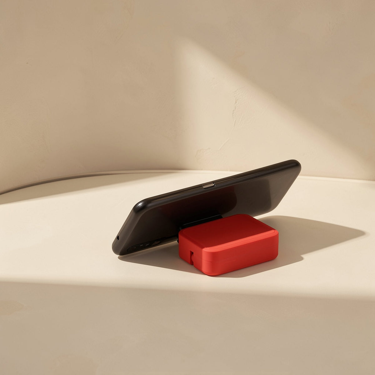 Trioflow Three-In-One TPE Data Cable – red cable case propped under a black smartphone, working as a small phone stand