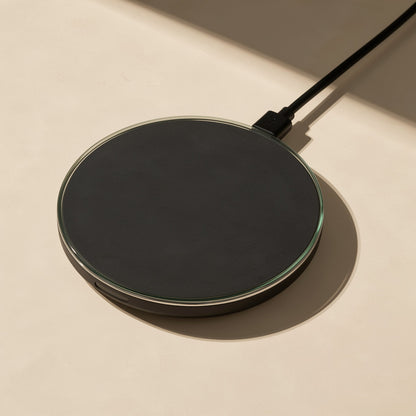 Voltflow Wireless Charger – black charging pad with a glass-edged top and attached black cable, lying flat in warm light