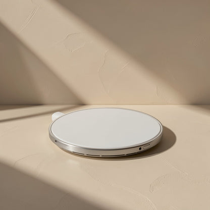 Voltflow – White version of the round charger with a silver rim and side vents, lying on a textured beige surface