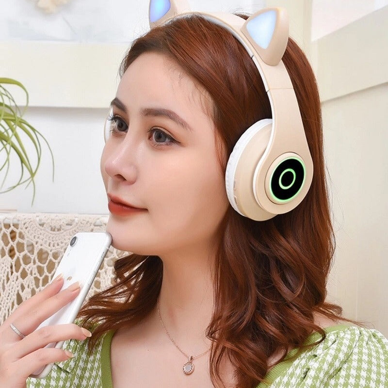 Purrtone – Woman wearing a cream cat ear headset with green glowing ring on the earcup, holding a phone