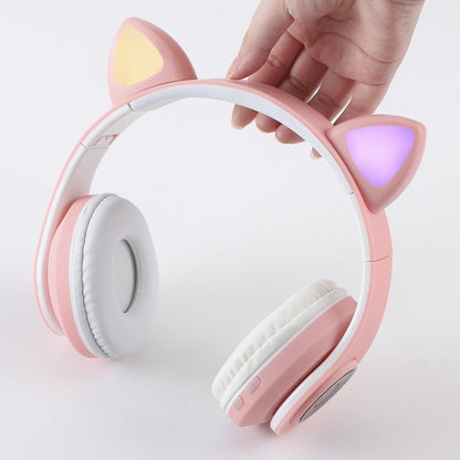 Purrtone Bluetooth Cat Ear Headset – hand holding a pink foldable cat ear headset with yellow and purple lit ears