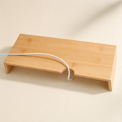 Bamboorise – Top-down view of a bamboo monitor stand with a curved cable notch and a white cable looped through it