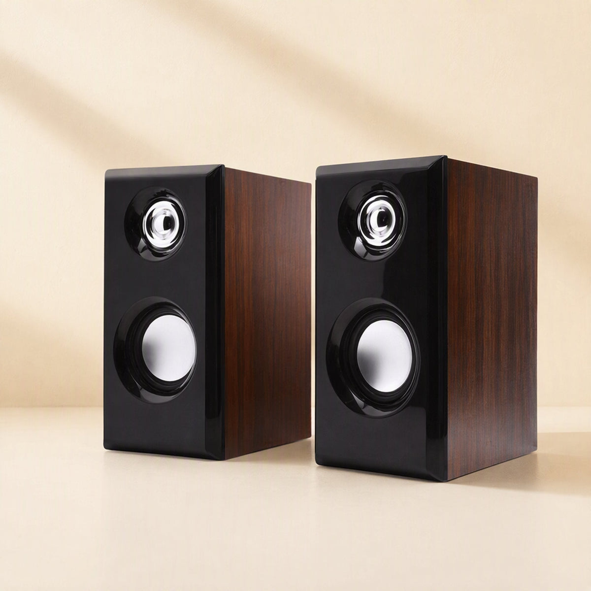 Woodtone – Angled view of two wood-grain speakers with black front panels, silver tweeters and round woofers