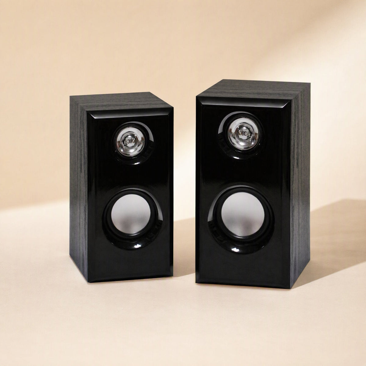 Woodtone – Pair of black wood-grain speakers on a beige surface, front view with tweeters and woofers