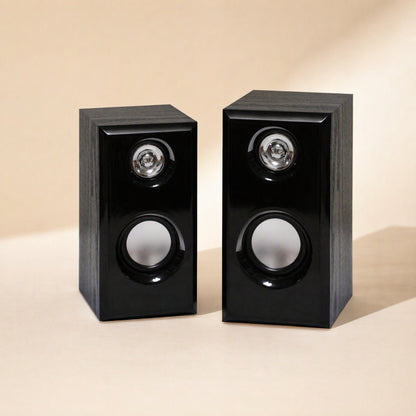 Woodtone – Pair of black wood-grain speakers on a beige surface, front view with tweeters and woofers