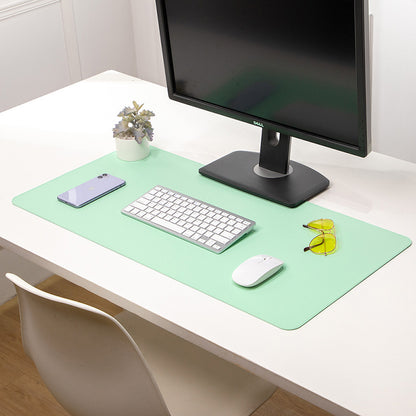 Deskhide – Mint green desk pad on a white desk under a monitor, holding a keyboard, mouse, phone and yellow glasses