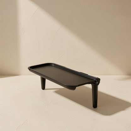 Screenstash Monitor Stand Storage Rack, black shelf with two legs, side view on a cream surface
