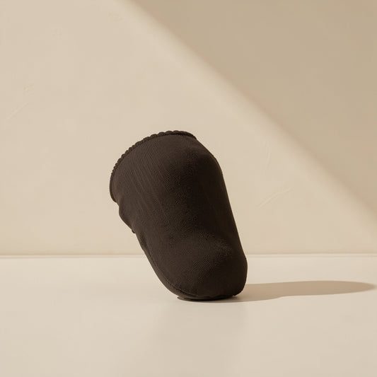Gripweave – Single black knit finger sleeve standing at an angle on a pale surface, with a scalloped open edge