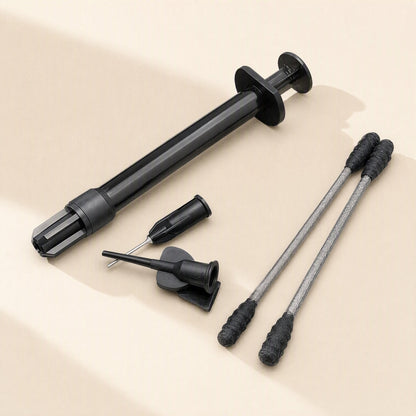 Meltlink – Black syringe with two dispensing tips, a tip cap and two black-tipped swabs laid out on beige