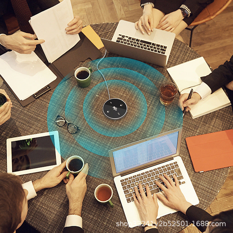 Clearwell – Round conference microphone on a meeting table among laptops, coffee cups and notes, with sound rings around it