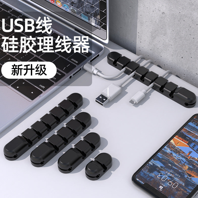 Wirenest Silicone Data Cable Organizer Clip in black, four sizes arranged beside a laptop and phone